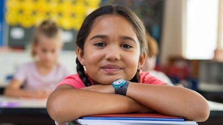 Young Latina student smiling in the classroom at her desk