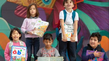 Diverse group of elementary kids holding picture books