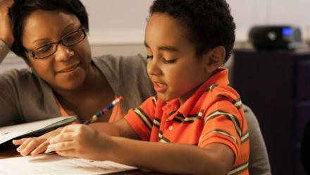 Mother and elementary school child looking at reading assignment together