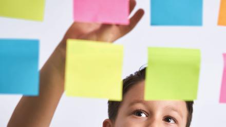 elementary student arranging colorful sticky notes on a board